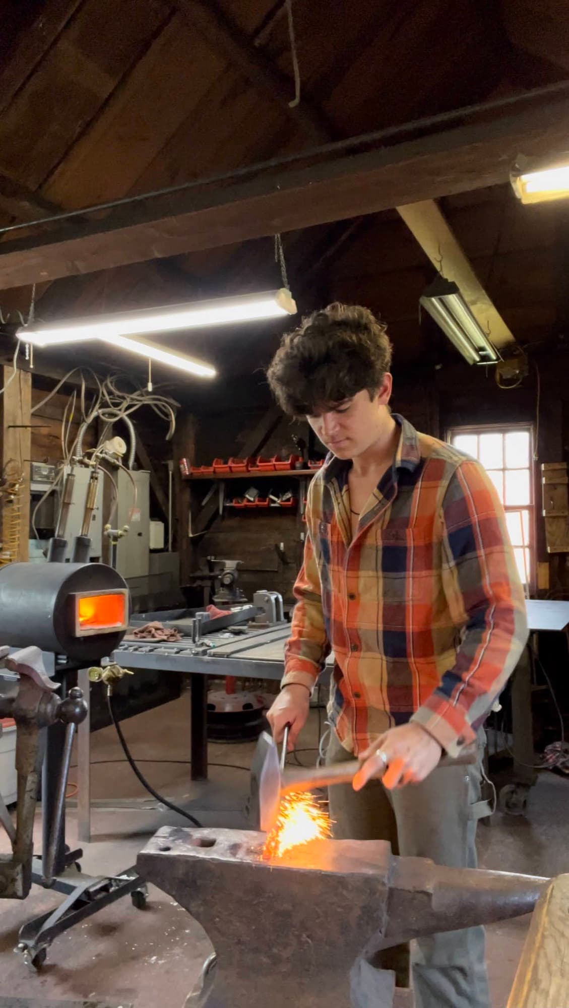 Judson Dunne hammering hot steel on the anvil, sparks off the work