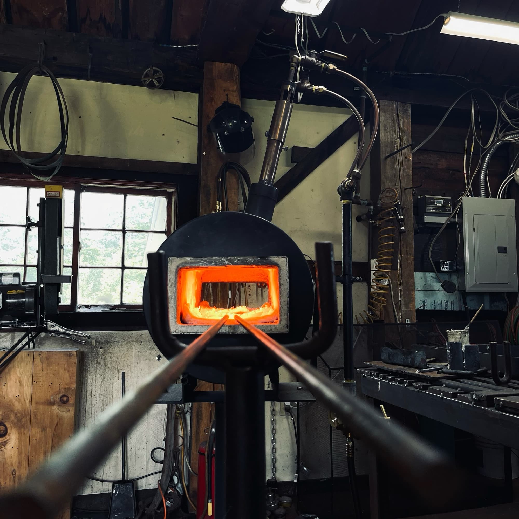 Two bars of steel heating in the mouth of the propane forge