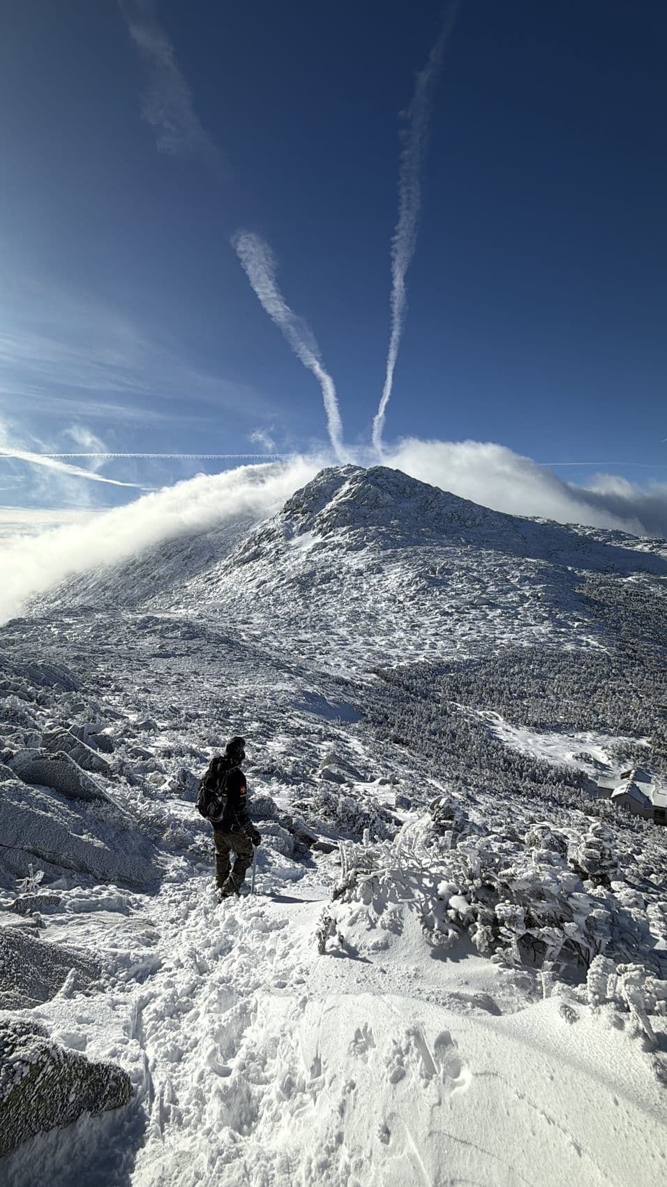 A snow-covered ridge under crossing contrails